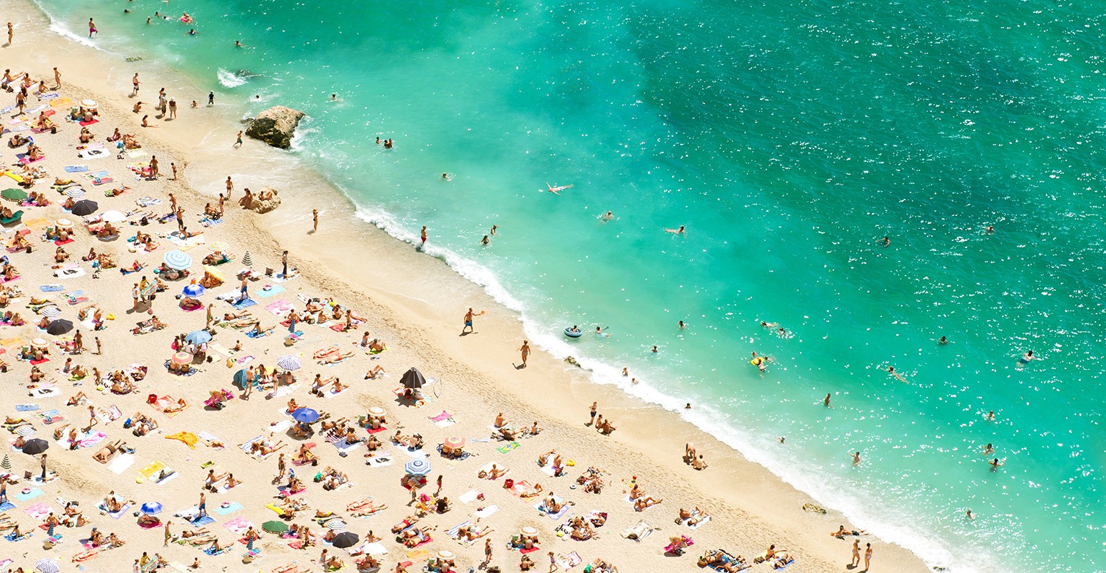 Beach of the Cote d'Azur with tourists, sunbeds and umbrellas on the hot summer day