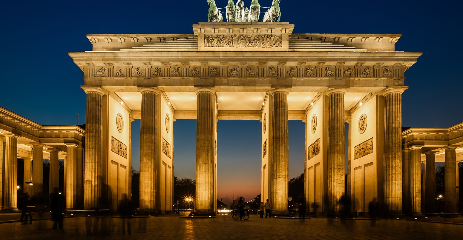 The floodlit Brandenburg Gate in Berlin with a few fleeting shadows of anonymous Berliner's - Symbol of Germany.