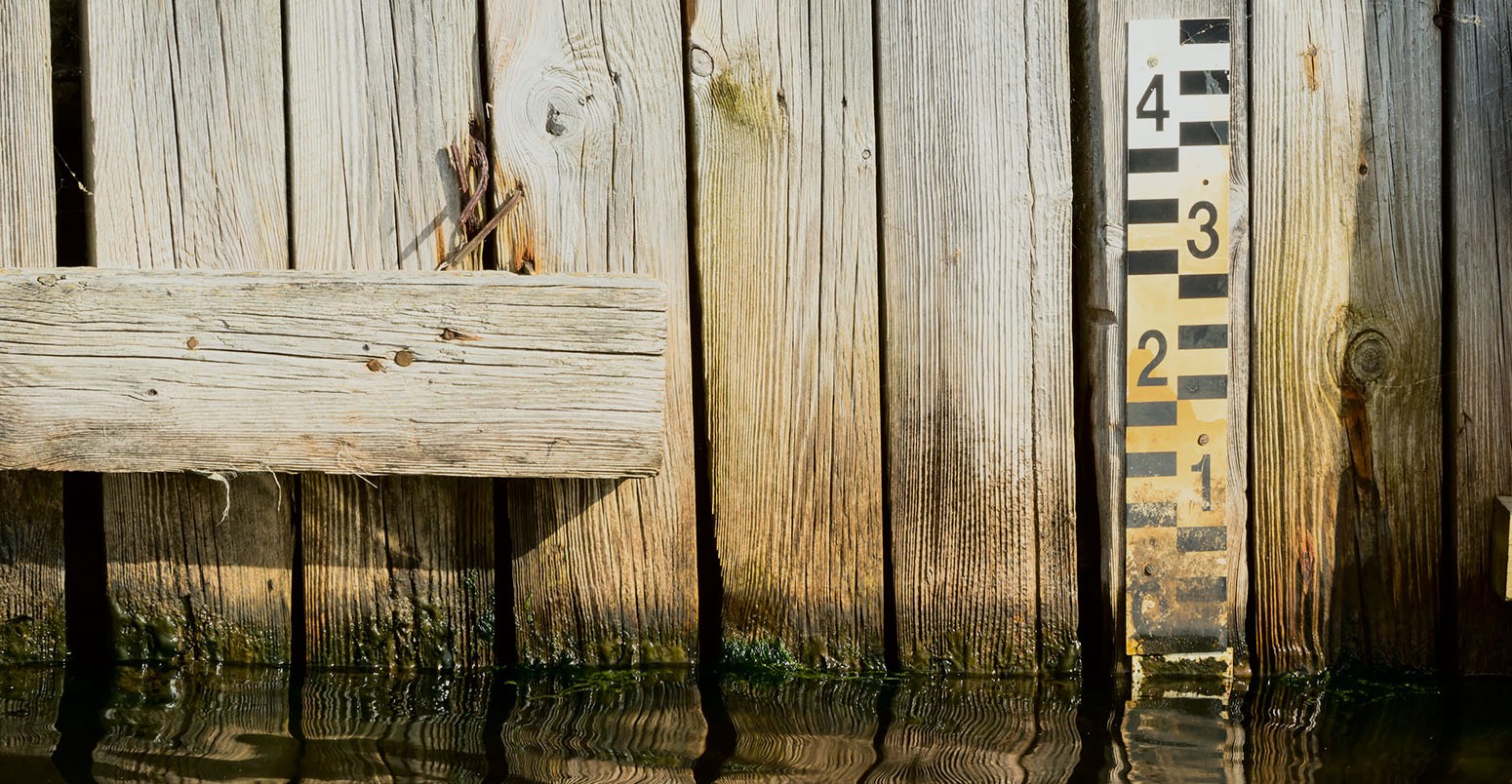 Water level marker on an old wooden bridge