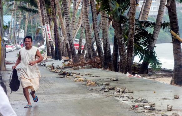 A man runs from the seafront as Super Typhoon Haiyan / Yolanda slams into the east coast sending palm trees, metal and rocks through the air