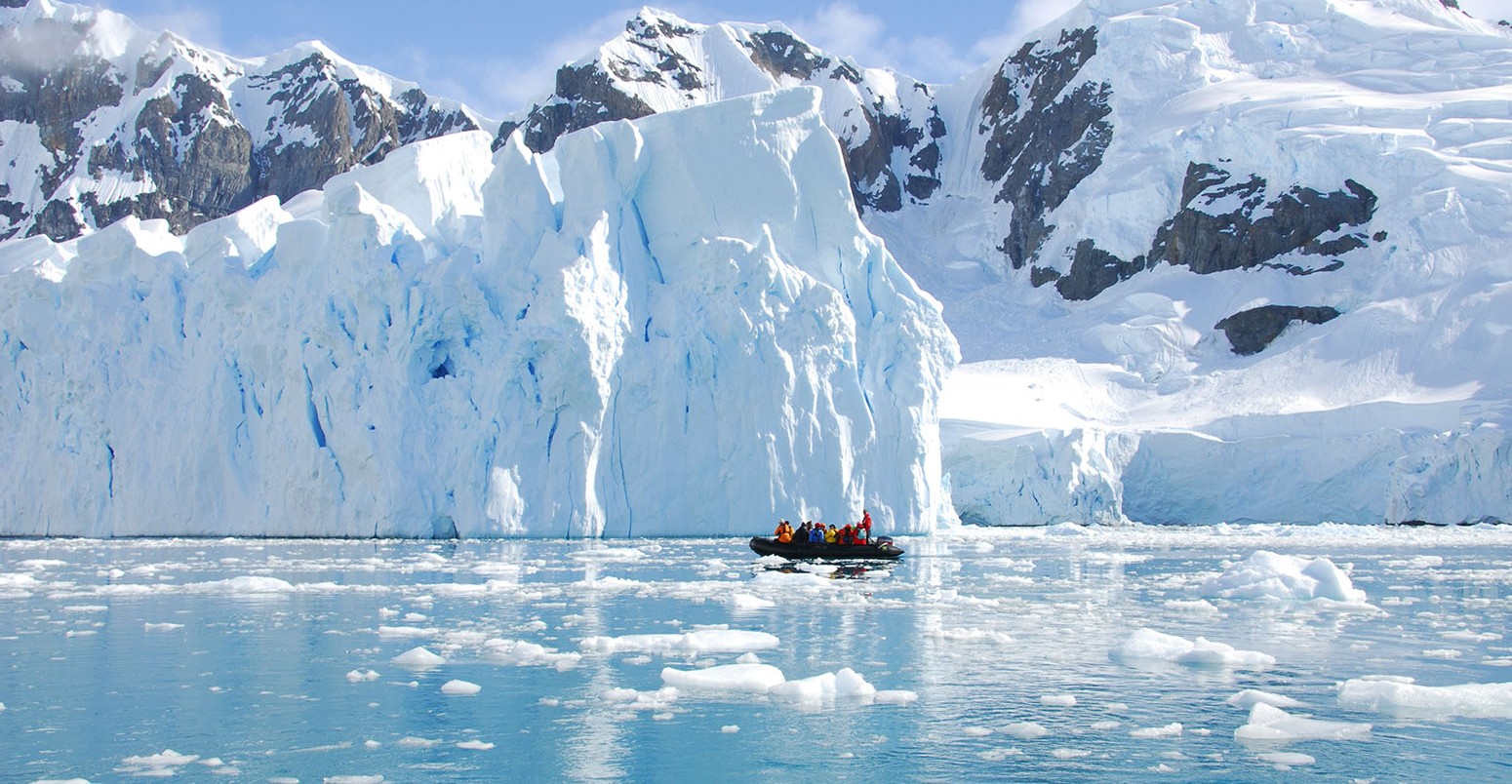 Iceberg off the coast of Antarctica with people in a boat