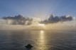 Evening sun behind clouds above the sea, Shetland Islands.