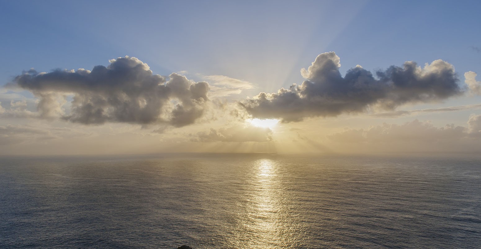 Evening sun behind clouds above the sea, Shetland Islands.