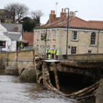 Members of the emergency service and police stand on the partially collapsed bridge in Tadcster, Yorkshire, northern England 30 December 2015 after heavy flooding caused the River Wharfe to break its banks. Residents have been evacuated from the village as Storm Frank hits many parts of the country.