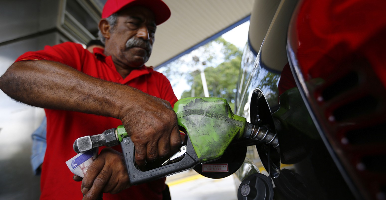 A man pumps gasoline at a service station in Caracas