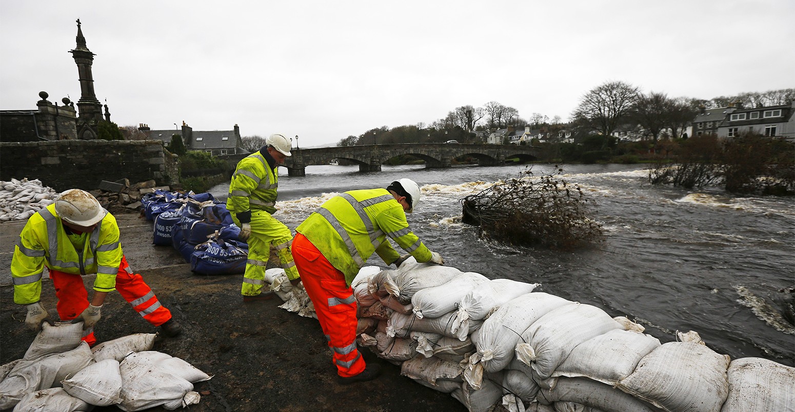 Council workers rebuild a wall with sandbags following flooding at Newton Stewart in Scotland, Britain December 31, 2015. Torrential rain and gale force winds have battered northern Britain cutting power to thousands of homes and forcing some to evacuate flooded streets in the third major storm in a month.