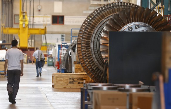 A worker walks past a gas turbine under construction at the gas turbines production unit of the General Electric plant in Belfort