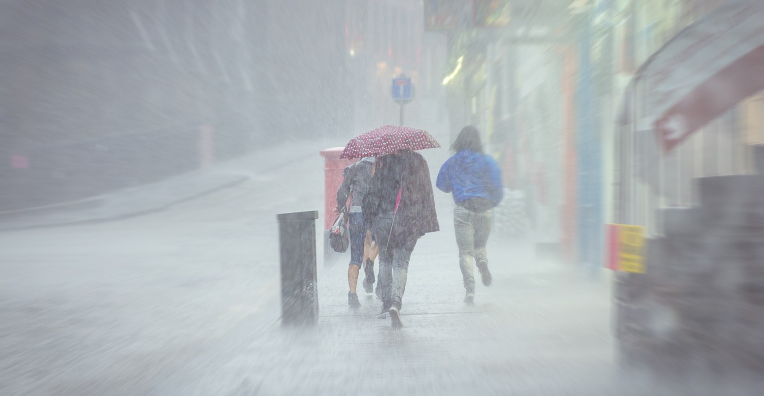 A group of girls hurry in the rain.