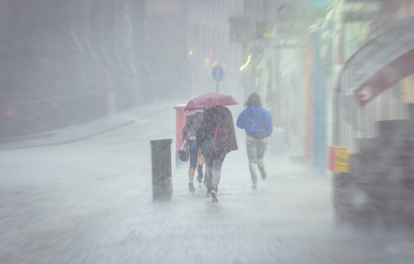 A group of girls hurry in the rain.