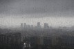 After heavy rainfall, the diffuse skyline of Barcelona is emerging in the twilight behind raindrops on a window