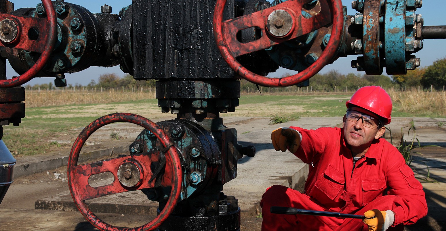 Oil worker pointing with his finger to oil field equipment