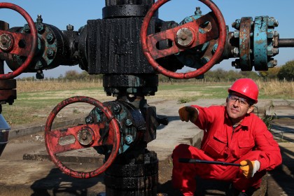 Oil worker pointing with his finger to oil field equipment