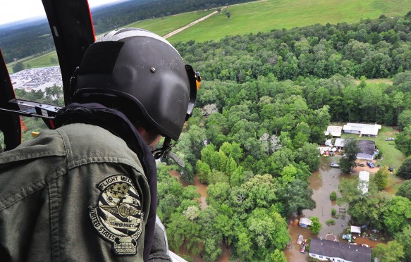 A Coast Guardsman looks out from an MH-65 Dolphin helicopter searching for stranded residents in Baton Rouge, LA on Aug. 15, 2016