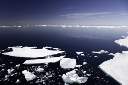 sheets of ice in antarctica, icebergs in the background, deep blue sunny sky