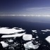 sheets of ice in antarctica, icebergs in the background, deep blue sunny sky