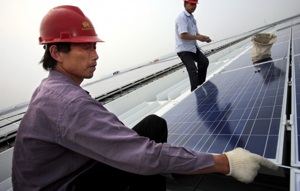 Workers install solar panels on the roofs of the Hongqiao Passenger Rail Terminal in Shanghai, China, 19 May 2010. Credit: Jiri Rezac/The Climate Group.