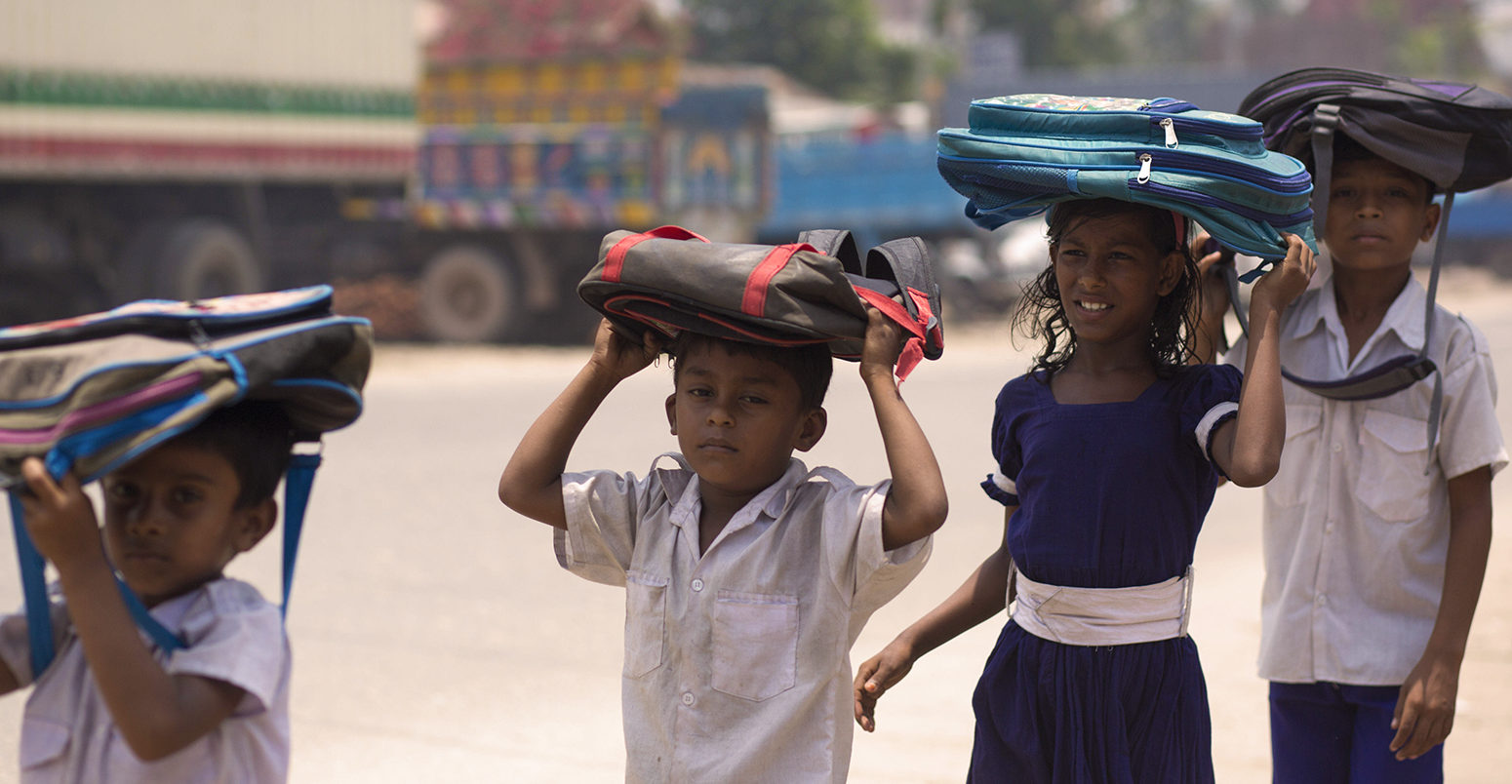 J77E94 Dhaka, Bangladesh. 22nd May, 2017. DHAKA, BANGLADESH - MAY 23 : School children return home after school keeping their school bag on head to save from heat of the sun in Dhaka, Bangladesh on May 23, 2017.Temperature in Dhaka reached 38 degrees Celsius on 23rd May. Credit: Zakir Hossain Chowdhury/ZUMA Wire/Alamy Live News