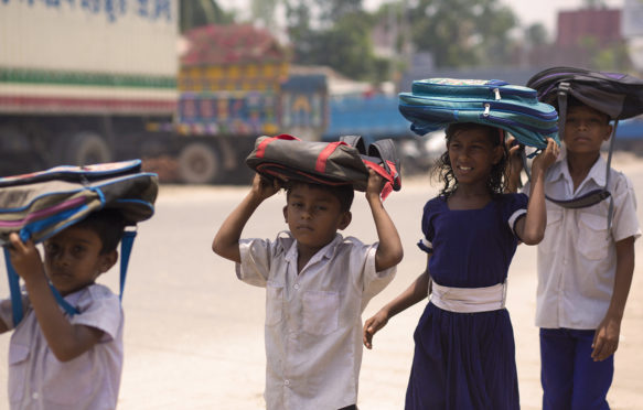 J77E94 Dhaka, Bangladesh. 22nd May, 2017. DHAKA, BANGLADESH - MAY 23 : School children return home after school keeping their school bag on head to save from heat of the sun in Dhaka, Bangladesh on May 23, 2017.Temperature in Dhaka reached 38 degrees Celsius on 23rd May. Credit: Zakir Hossain Chowdhury/ZUMA Wire/Alamy Live News