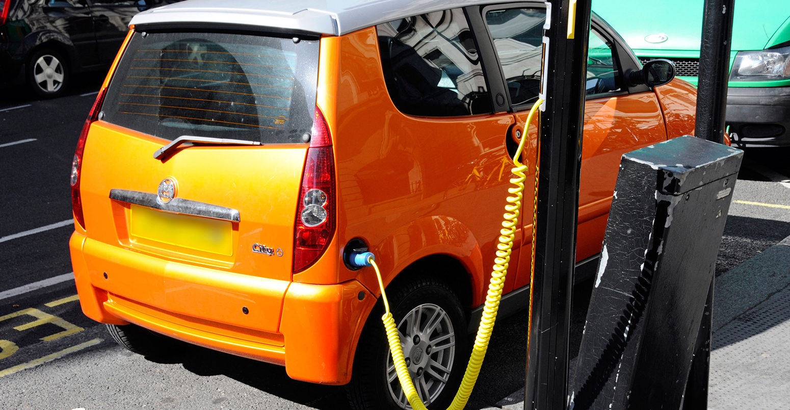 Electric car charging station cable hooked up to recharging bollard London UK