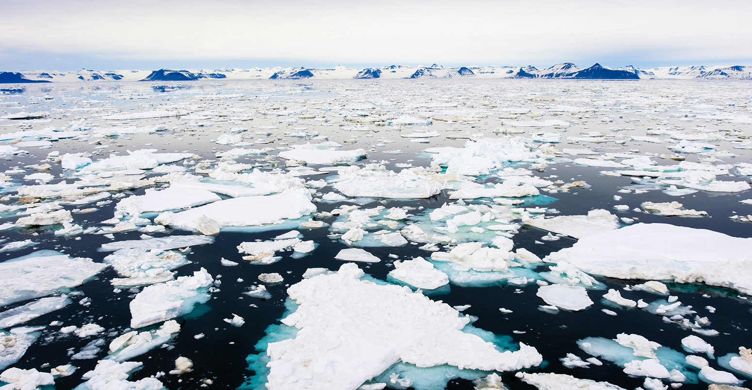 KDX99H Offshore view across sea ice floe to mountains on east coast at 2 am in arctic summer. Spitsbergen island, Svalbard archipelago, Norway, Scandinavia.