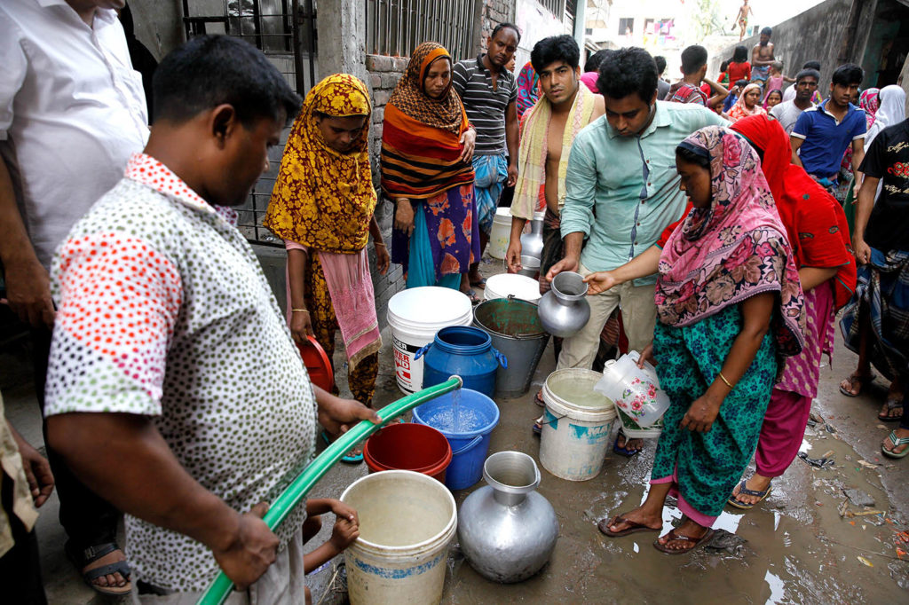 Bangladeshi women and children waiting for drinking water inside the street in Dhaka. Credit: age fotostock / Alamy Stock Photo KP23YA