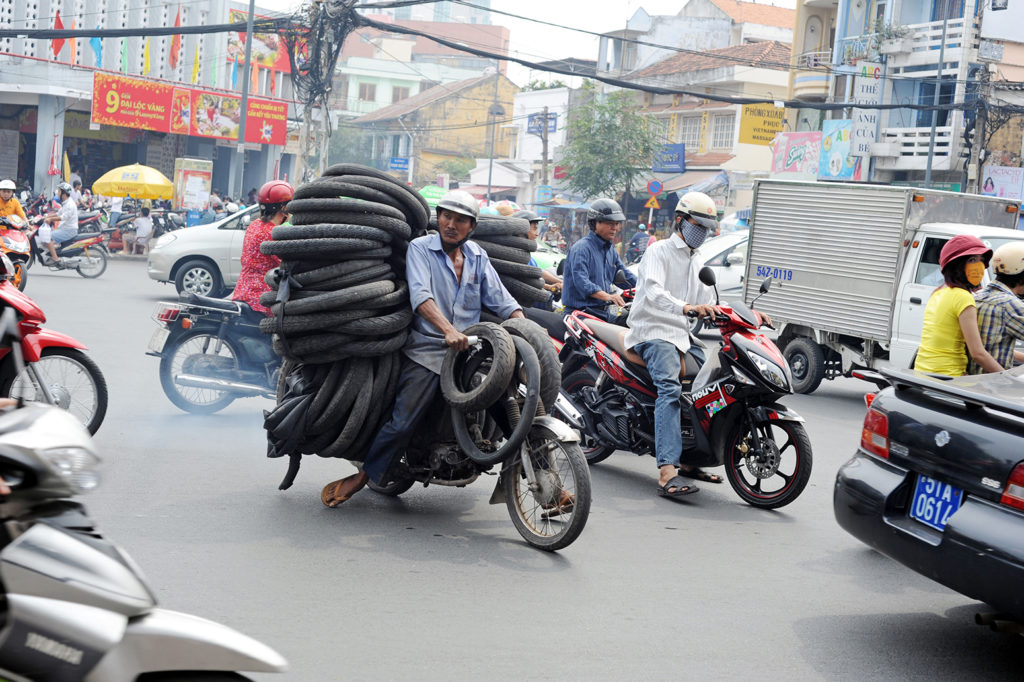 DFJ7E0 A man carry pile of tires on autobike in Ho Chi Minh City, Vietnam.