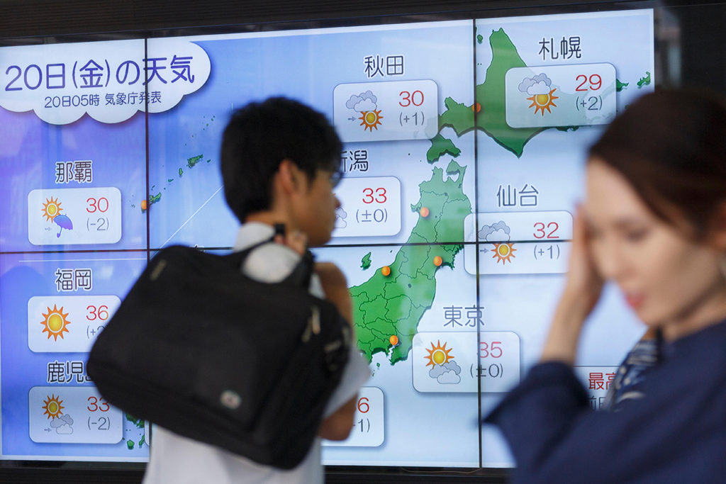 PA174A Tokyo, Japan. 20th July, 2018. Pedestrians walk past an electronic screen showing Japan's temperatures on July 20, 2018, in Tokyo, Japan. The hot weather saw temperatures rise to as high as 40.7 C degrees in central Japan on Wednesday and the heatwave is expected to last at least until the end of the month. Nationwide over 10,000 people have been hospitalized as a result of the heat.