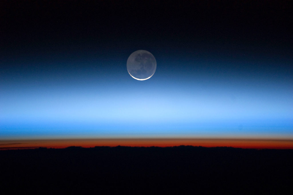 Moon with orange-coloured troposphere band, the lowest and most dense portion of the Earth's atmosphere. The troposphere ends abruptly at the tropopause, which appears in the image as the sharp boundary between the orange - and blue - coloured atmosphere. Credit: NASA Photo / Alamy Stock Photo. D7KRFX