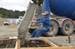EFA7E6 A builder directs wet concrete from a cement truck into the foundations of a large building.