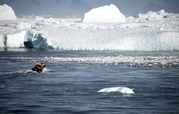 A boat transports people towards a glacier in Antarctica. Credit: Robert German / Alamy Stock Photo. M9B4XN