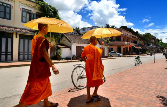 Two monks shading from the sun in Loungprabang, Laos. Credit: Nopadol Uengbunchoo / Alamy Stock Photo. HWPG36