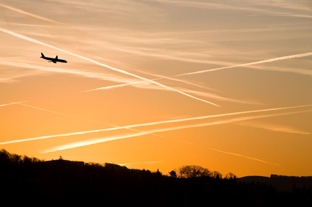 Contrails over a dawn sky near Ambleside Cumbria, UK. Credit: Ashley Cooper / Alamy Stock Photo. C2K5CG