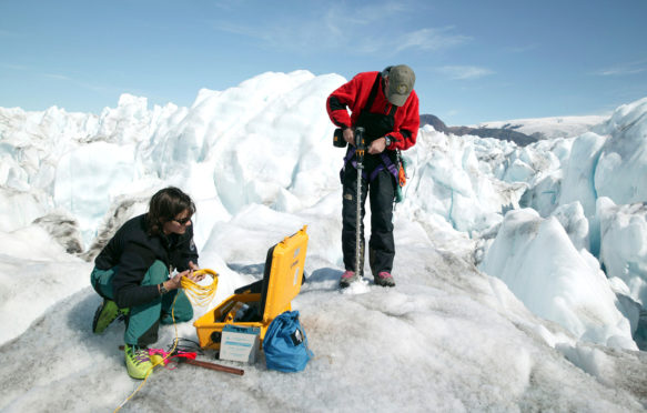 Glaciologists measuring the rate of movement on the Kangerdlussuaq glacier, Greenland. Credit: Steve Morgan / Alamy Stock Photo. DFB4EE