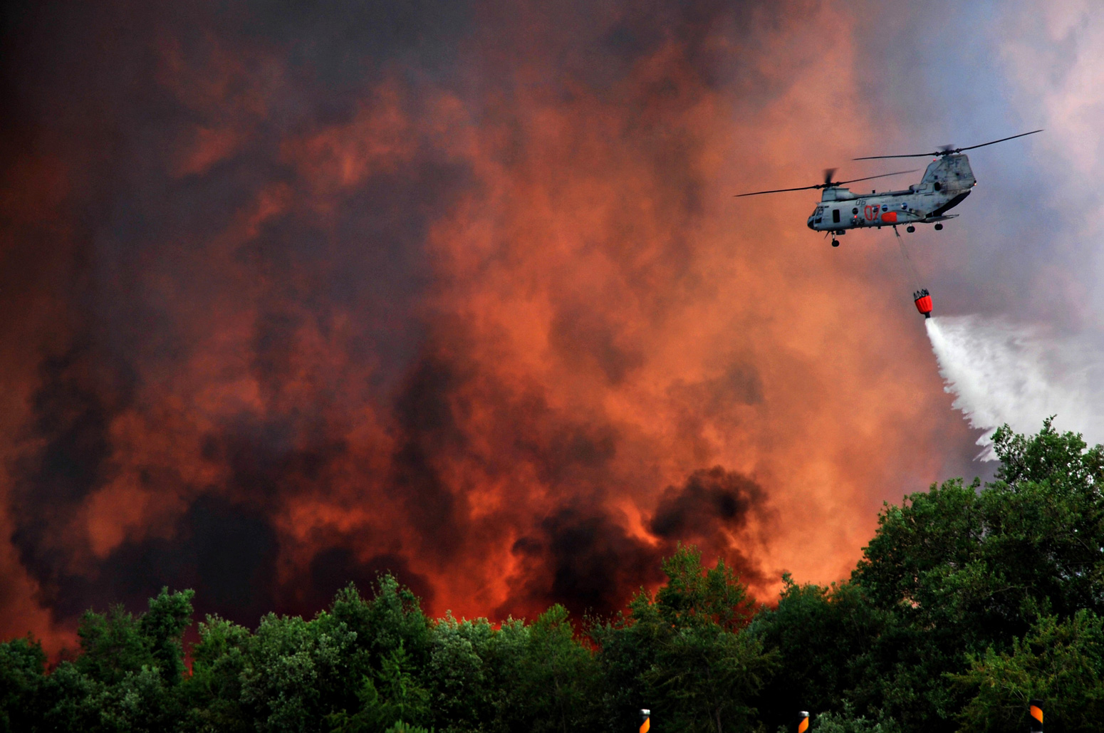 A US Marine Corps helicopter carries water using a Bambi bucket to help fight the Tomahawk and Las Pulgas wildfires as they burn the foothills 17 May 2014 around Camp Pendleton, California. Credit: US Marines Photo / Alamy Stock Photo
