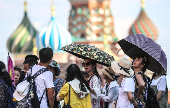 People take shelter under umbrellas during a heatwave in Moscow, 3 August 2018. Credit: ITAR-TASS News Agency / Alamy Stock Photo.