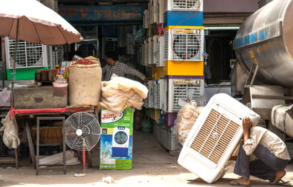 An air conditioning vendor prepares a unit for sale in Delhi, India. Credit: Kevin Su / Alamy Stock Photo.