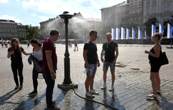 People cooling down in the spray of water mist as temperatures soar into the thirties in Krakow Poland 2018