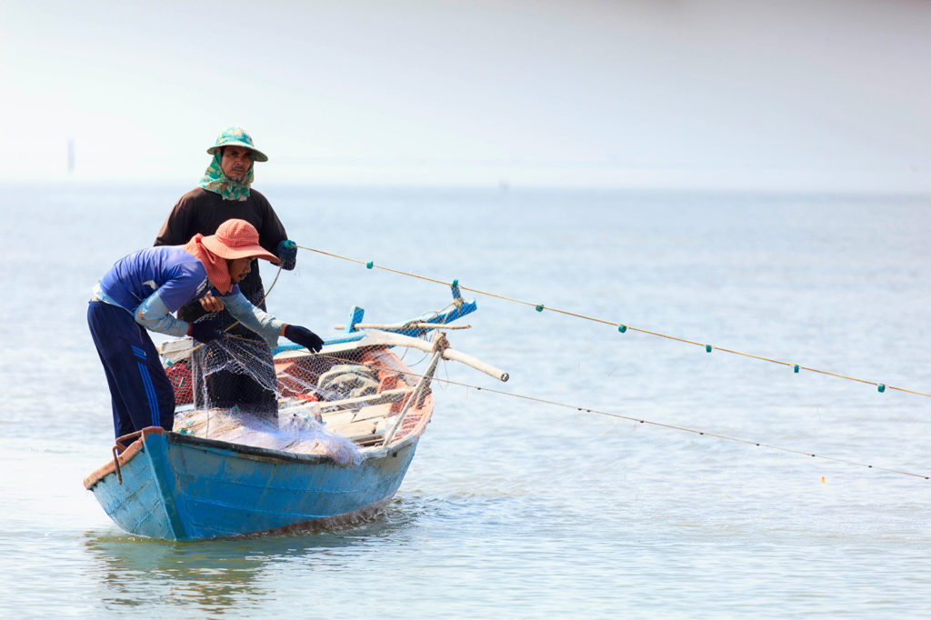 Fishermen with a cast net in the South China Sea, Kampot, Cambodia. Credit: John Michaels / Alamy Stock Photo. MFW9K3