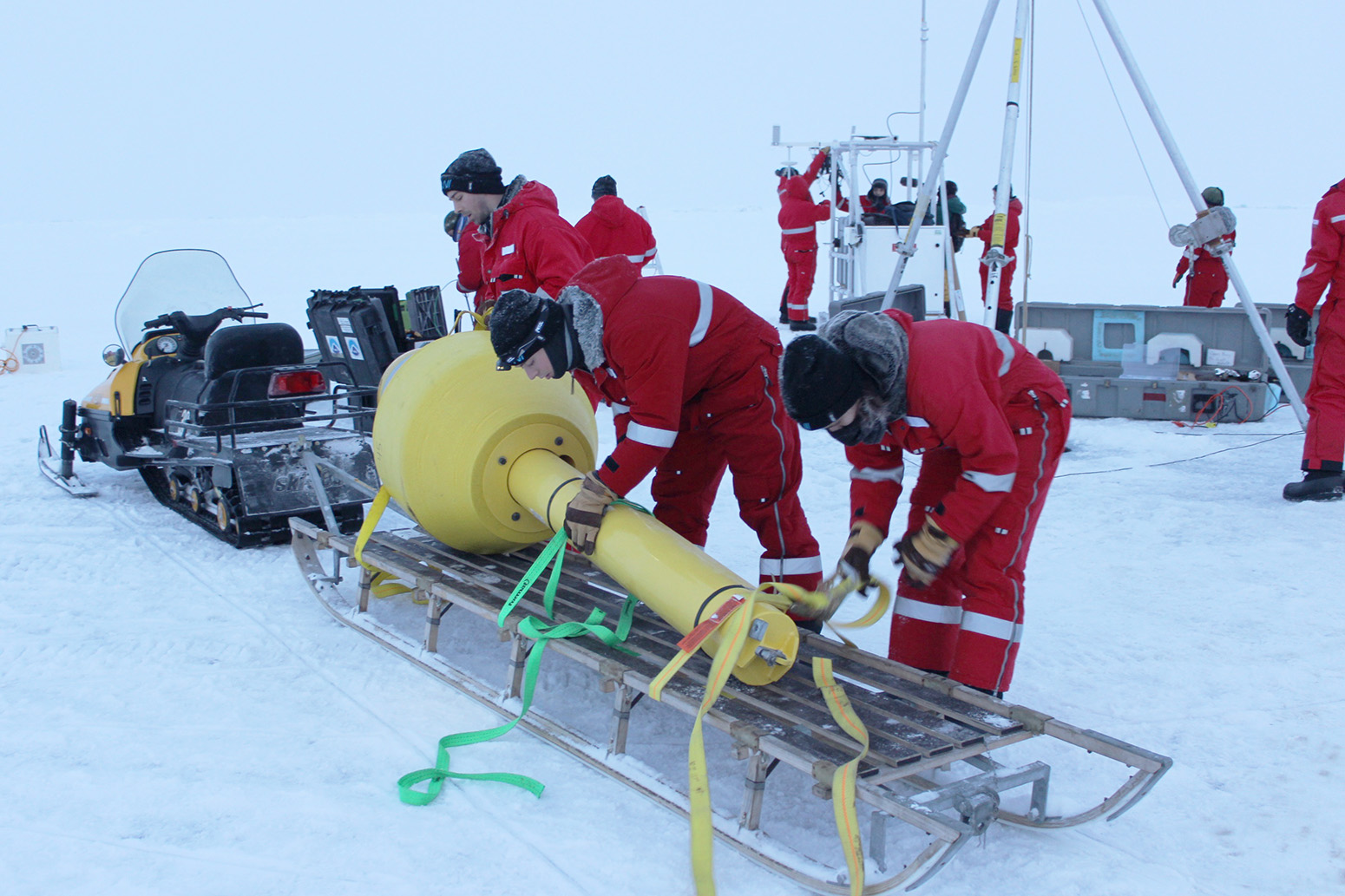 A yellow float, part of a specialised ocean buoy, is loaded off a snowmobile in the Central Arctic Ocean. 