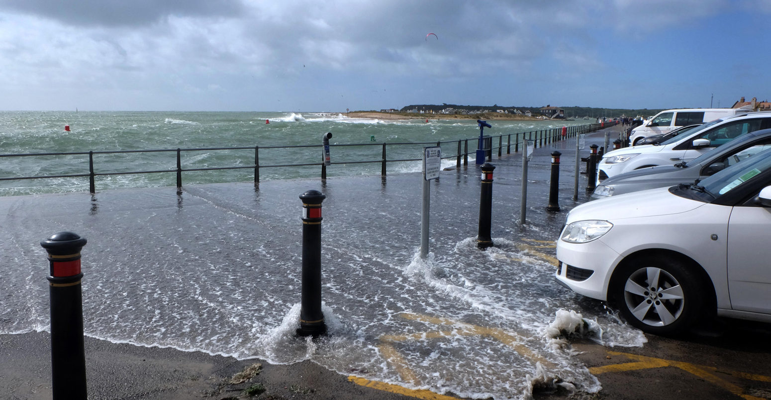 Coastal flooding into car park and walkway, Mudeford quay, Dorset, UK. Credit: Helen James / Alamy Stock Photo