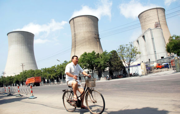 A cyclist rides past a coal-fired power plant in Beijing, China. Credit: Imaginechina Limited / Alamy Stock Photo. W9CEBT