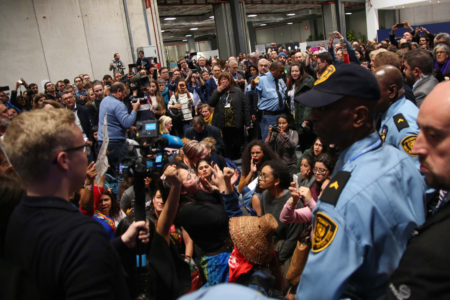 Demonstrators sit down in the corridors, occupying the space and delaying the high-level proceedings. Photo by Kiara Worth