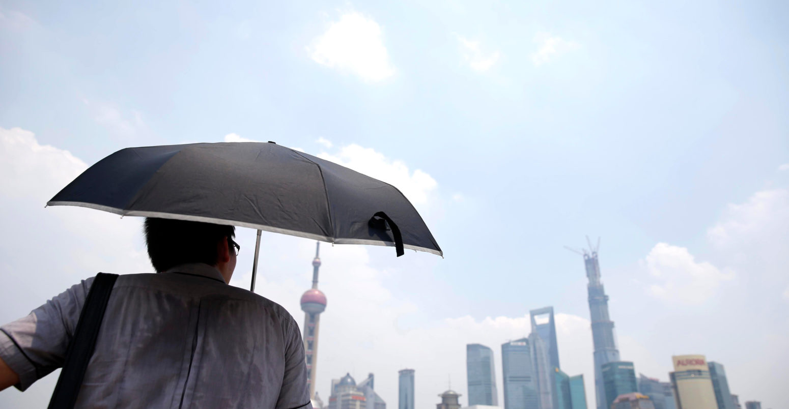 A man shields himself from the sun during a heatwave in Shanghai, China. Credit: Imaginechina Limited / Alamy Stock Photo. W93HRR