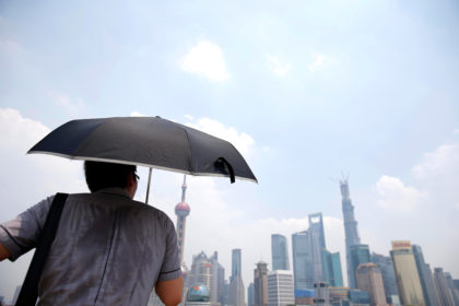 A man shields himself from the sun during a heatwave in Shanghai, China. Credit: Imaginechina Limited / Alamy Stock Photo. W93HRR