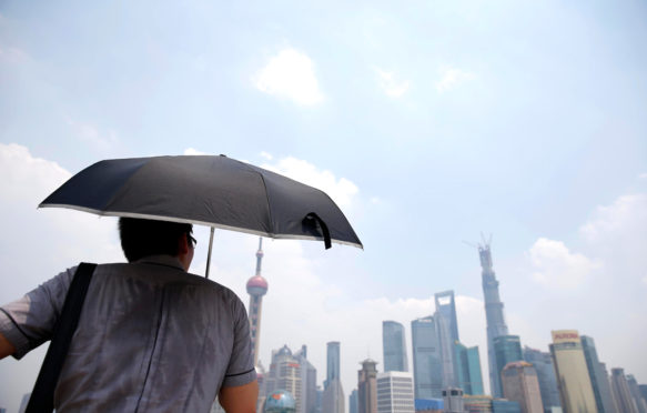 A man shields himself from the sun during a heatwave in Shanghai, China. Credit: Imaginechina Limited / Alamy Stock Photo. W93HRR