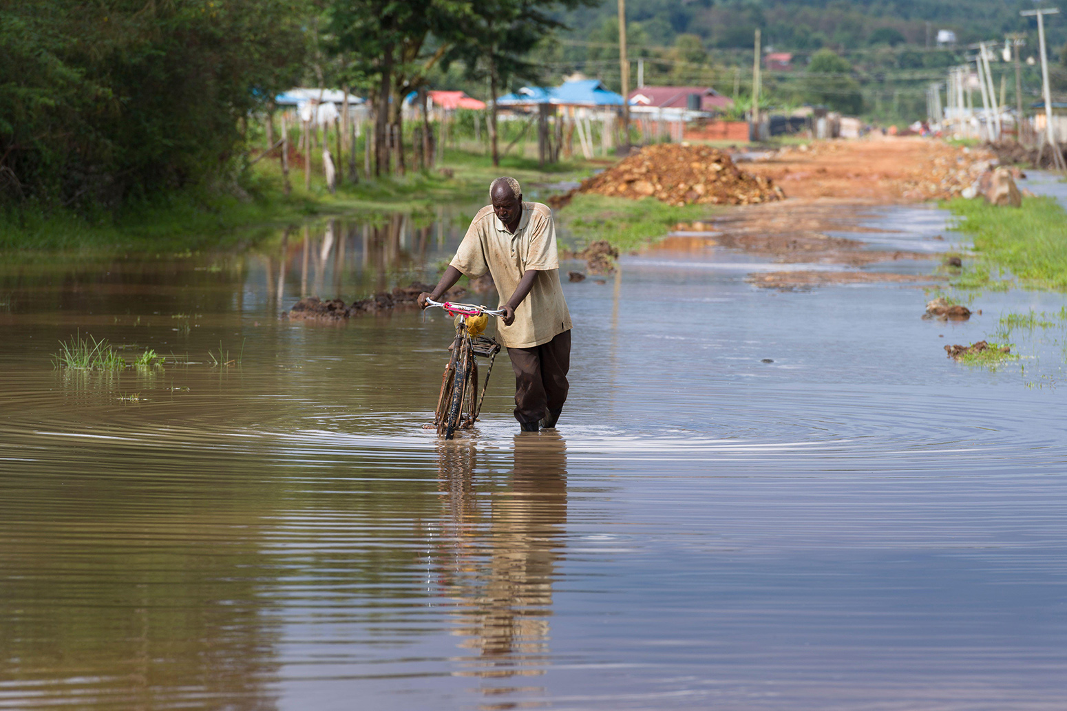 Man wading through flood water outside Nairobi, Kenya, 13 January 2020. Credit: Alex MacNaughton / Alamy Stock Photo. 2B5GMJ9