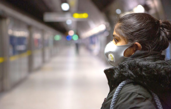 Commuters wearing face masks on the London Underground travelling during the COVID-19 outbreak, March 2020. Credit: Transport for London / Alamy Stock Photo. 2BB5C5Y