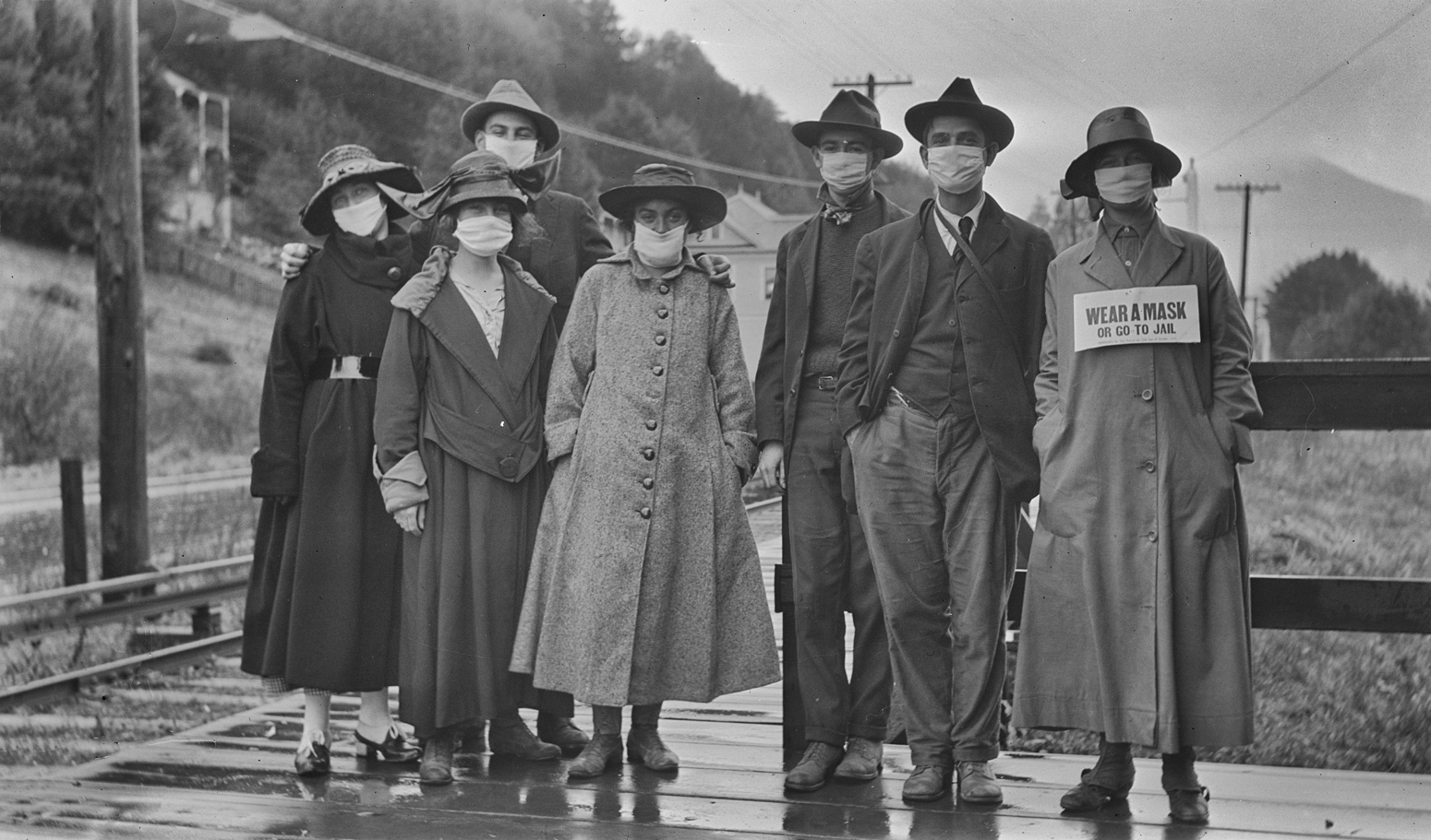 A group of people standing outdoors wearing masks over their mouths, probably taken during the Spanish Flu epidemic of 1918. Credit: Niday Picture Library / Alamy Stock Photo