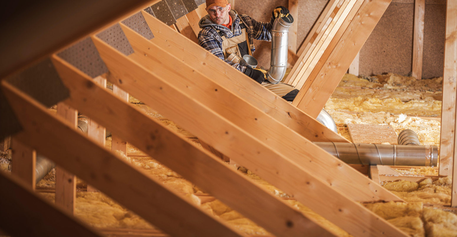 Worker installing heating and air conditioning system in an insullated attic. Credit: Tomasz Zajda / Alamy Stock Photo