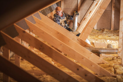 Worker installing heating and air conditioning system in an insullated attic. Credit: Tomasz Zajda / Alamy Stock Photo